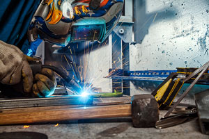 Welder using welding equipment giving off blue lights and red sparks