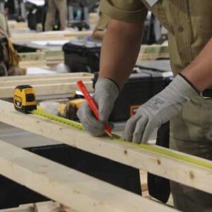 Worker in gloves measuring wood