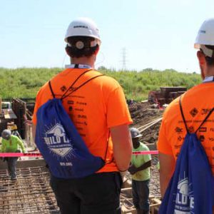 Students in hard hats looking at construction workers.